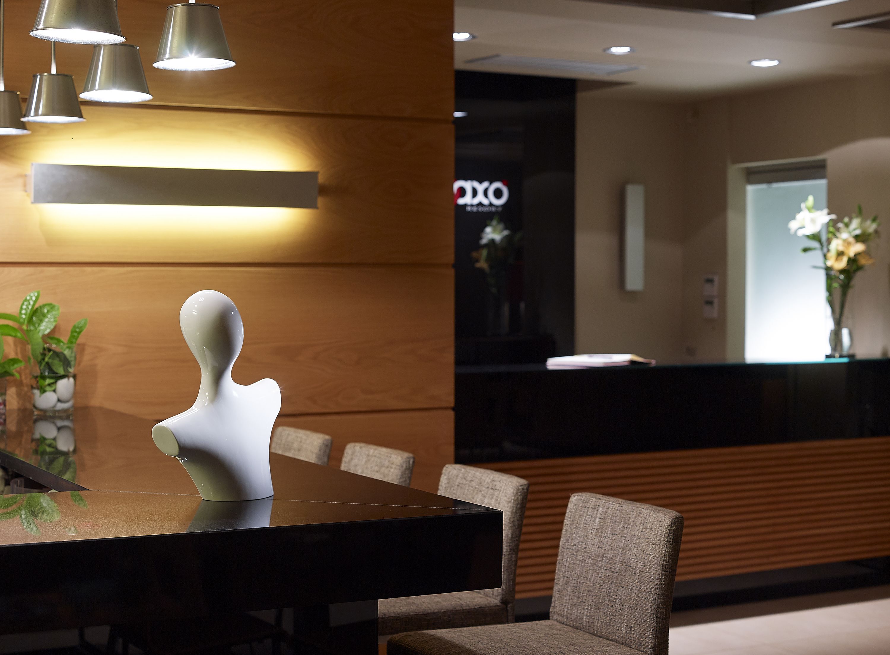 Una recepción de diseño moderno, un panel de pared de madera y un área de descanso con sillas.