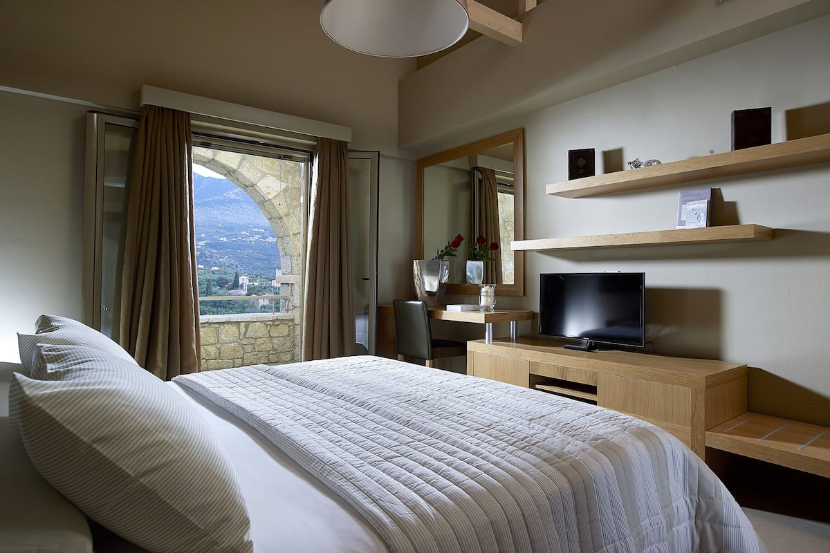 Ein Hotelzimmer mit Bett, Fernseher, Schreibtisch und Blick auf die Berge.