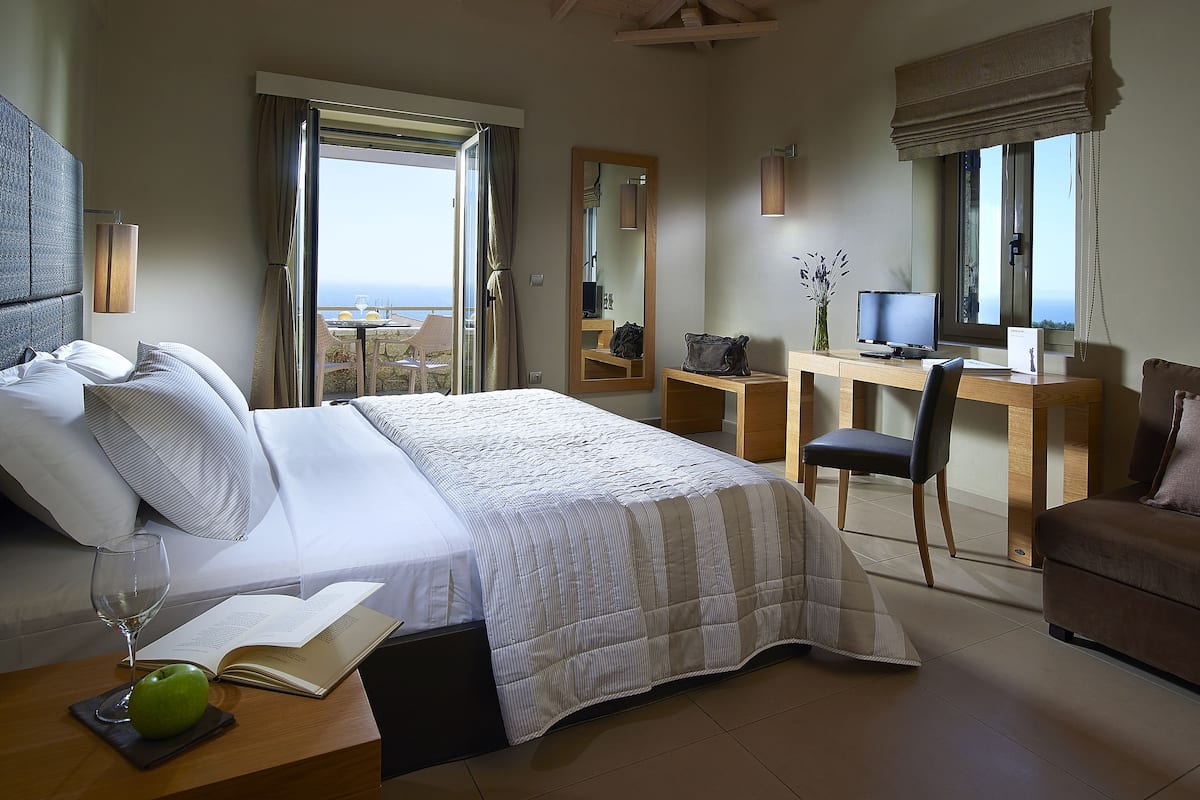 Ein Hotelzimmer mit Bett, Schreibtisch, Stuhl, Fernseher und Meerblick.