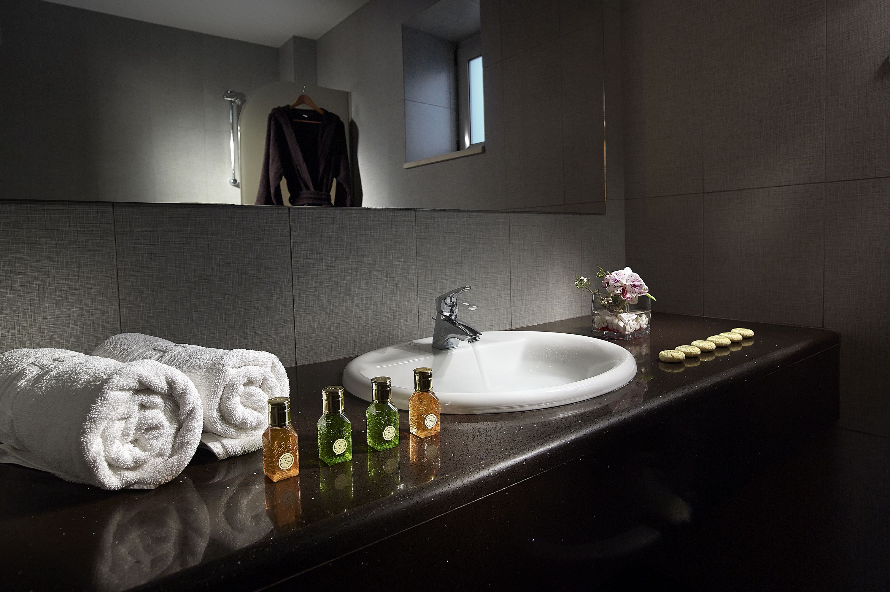 Une salle de bain moderne avec un grand miroir, un lavabo blanc et des serviettes soigneusement pliées.