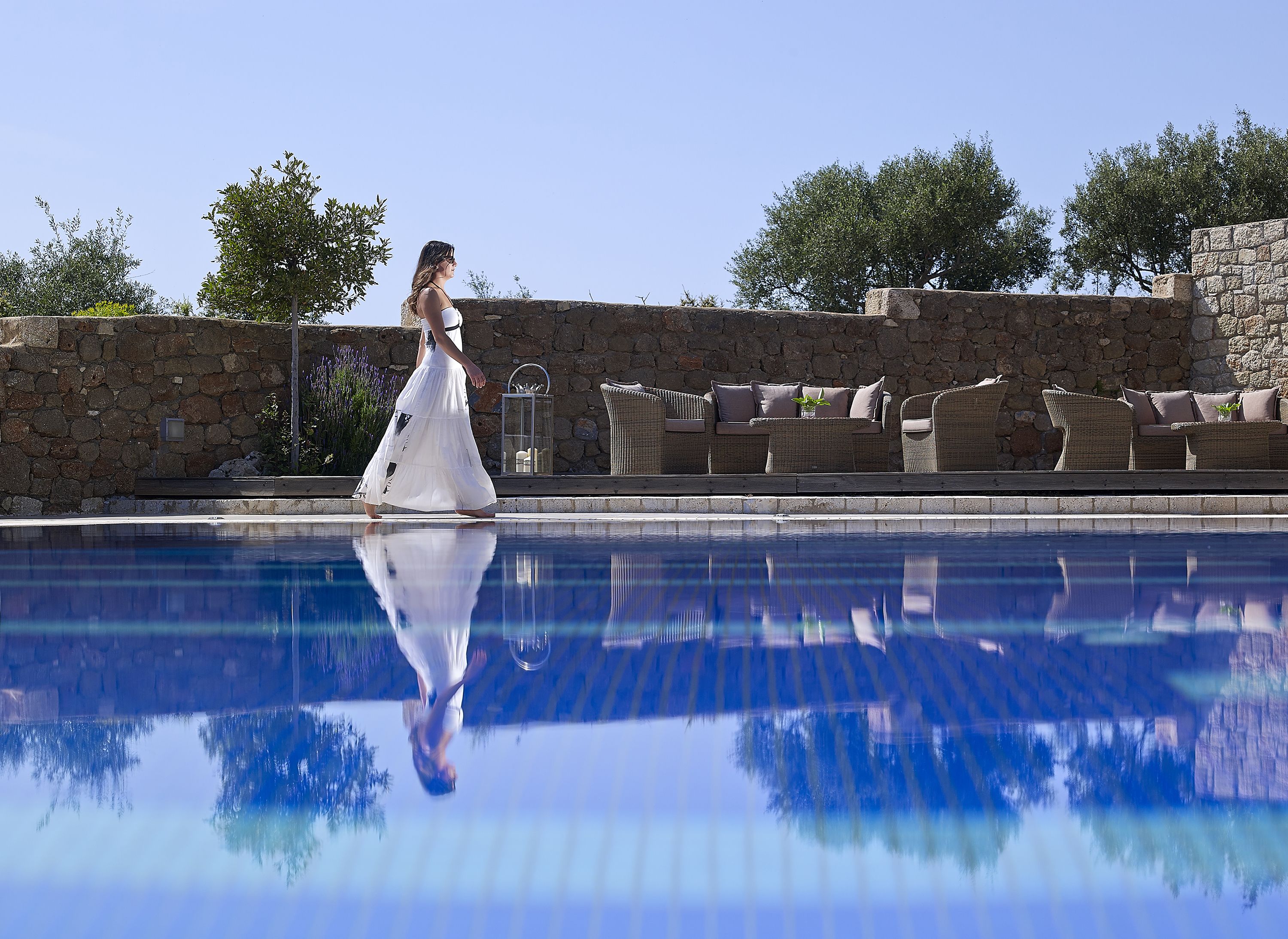 A pool area with stone walls and wicker furniture.
