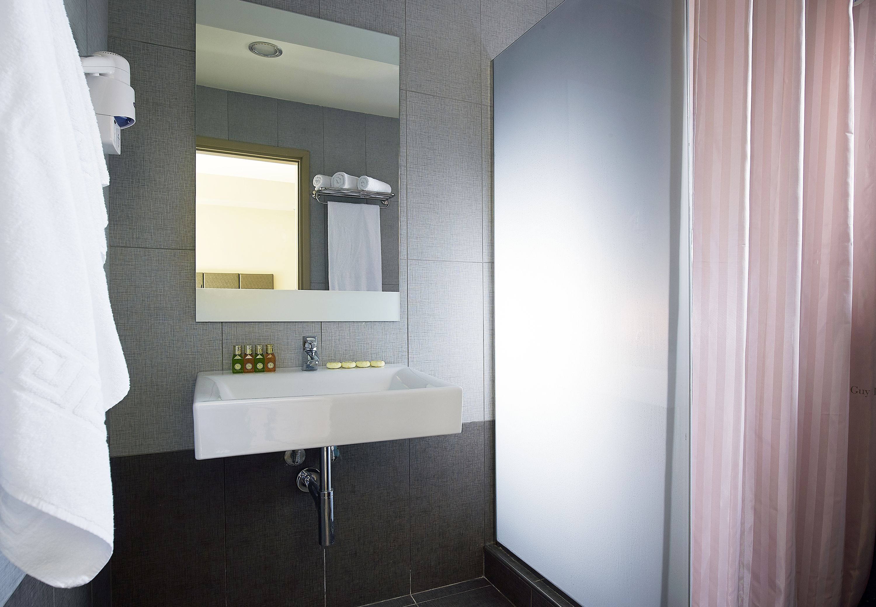 A modern bathroom with a white sink, mirror, and towel rack.