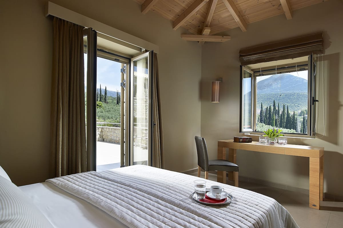 Ein Schlafzimmer mit Bett, Schreibtisch und Blick auf eine gebirgige Landschaft.
