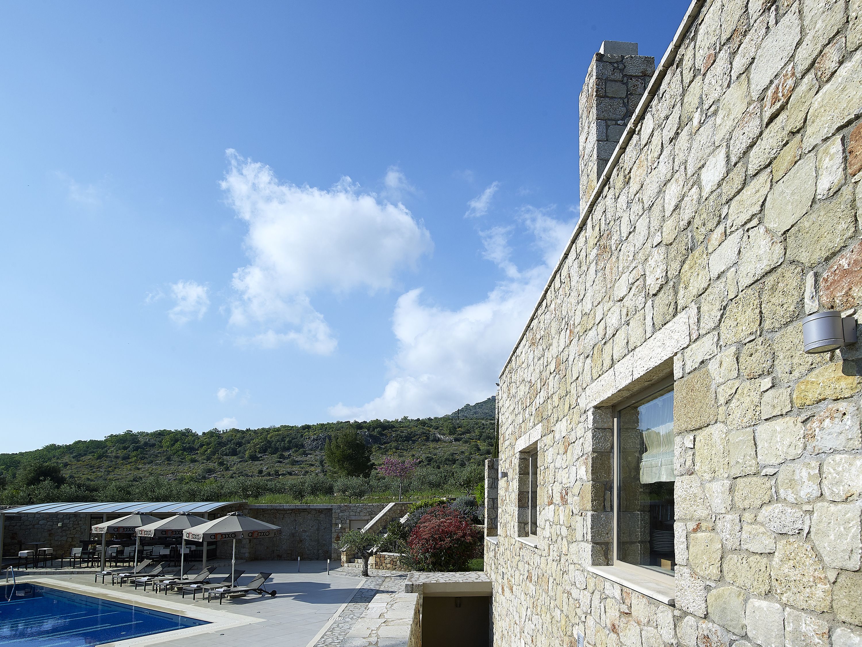 Un bâtiment en pierre doté d’une piscine, d’un espace extérieur aménagé et offrant une vue sur une colline.