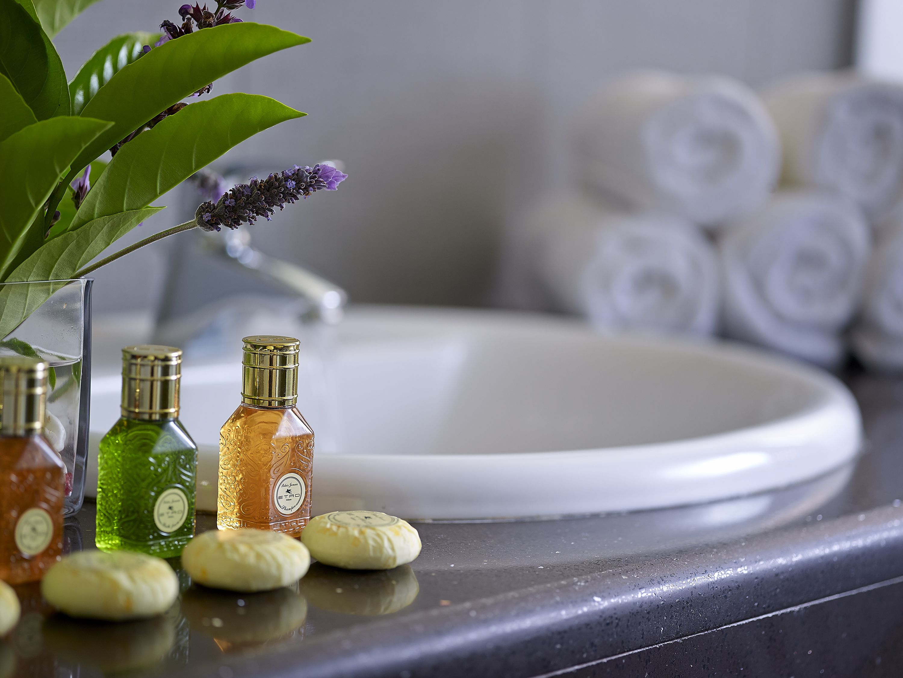 A bathroom counter with toiletries, a sink, and towels.