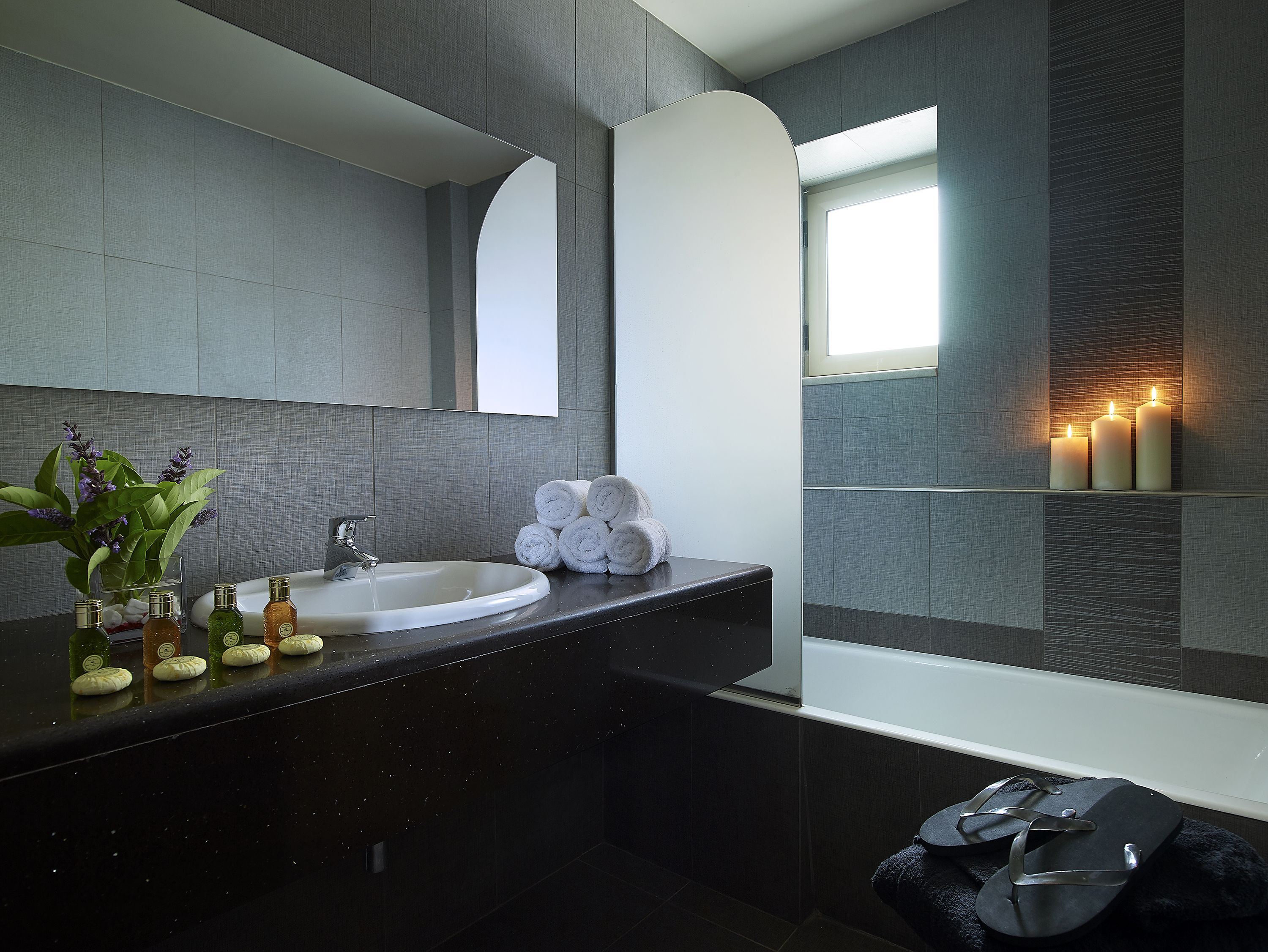 Un baño moderno con un lavabo redondo, un espejo, una ventana y una bañera.