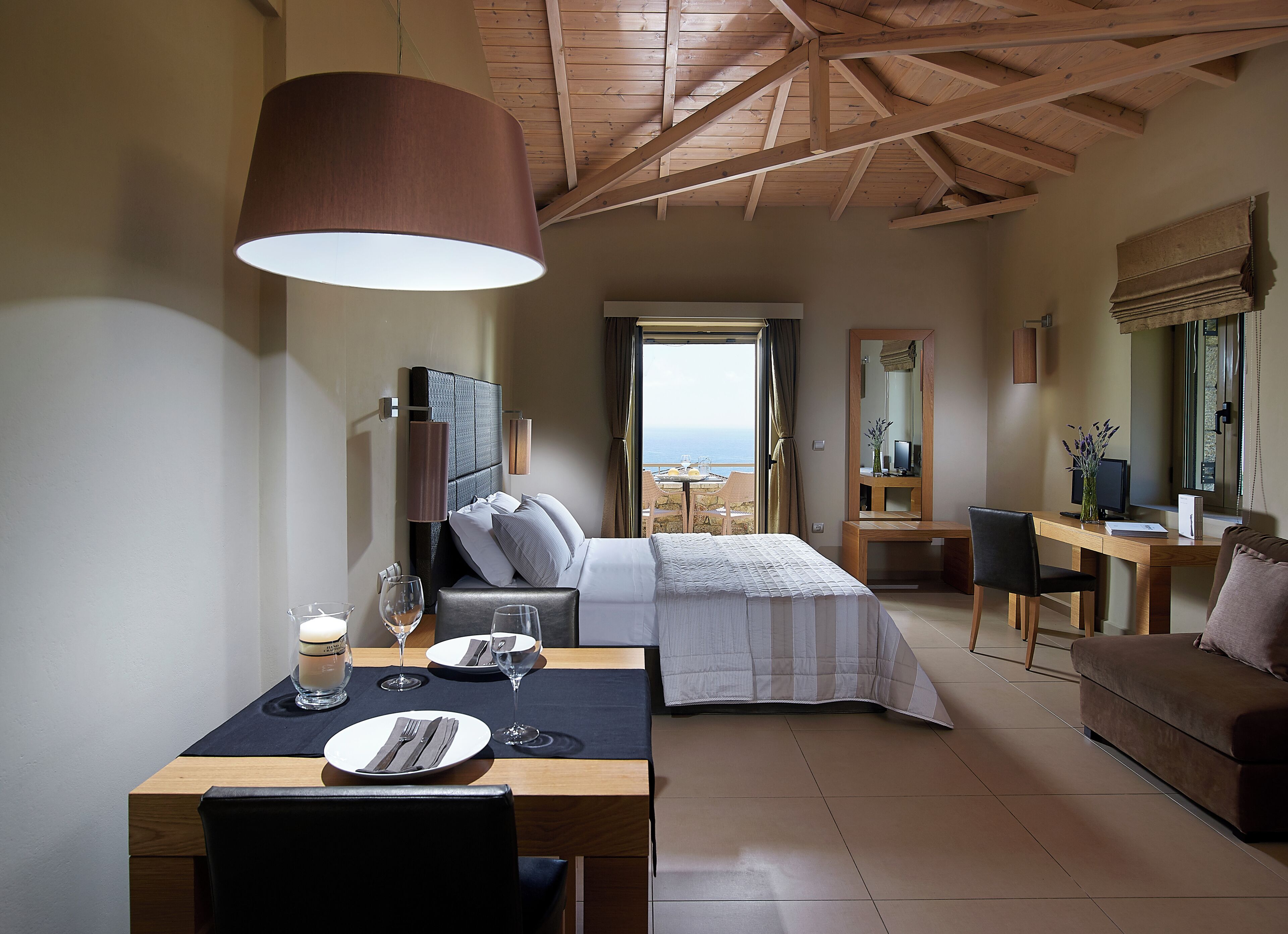 A bedroom with a bed, a desk, a chair, and a dining table with a lamp.