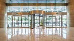 Een moderne lobby met een draaideur, glazen wanden en een gepolijste vloer.