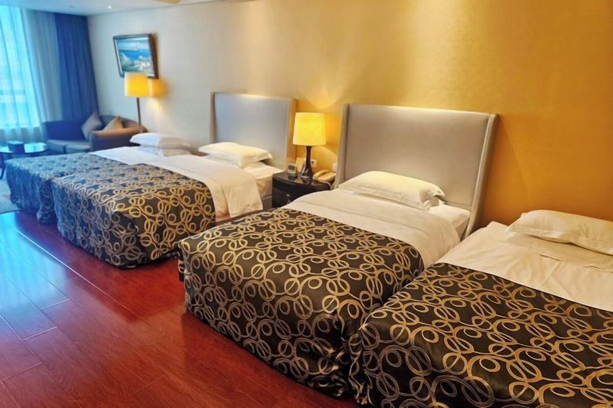 Habitación de hotel con tres camas, piso de madera y un cuadro en la pared.