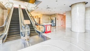 Een modern interieur met een roltrap, een pilaar en een receptiebalie.