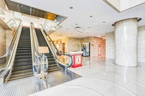 A modern interior with an escalator, a pillar, and a reception area. - Hua Bin International Hotel (Beijing)