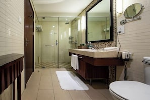 A modern bathroom with a glass shower enclosure, a large mirror, and a white toilet. - Hua Bin International Hotel (Beijing)