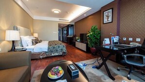 Een hotelkamer met een bed, bureau, stoel, lamp en een bloempot.