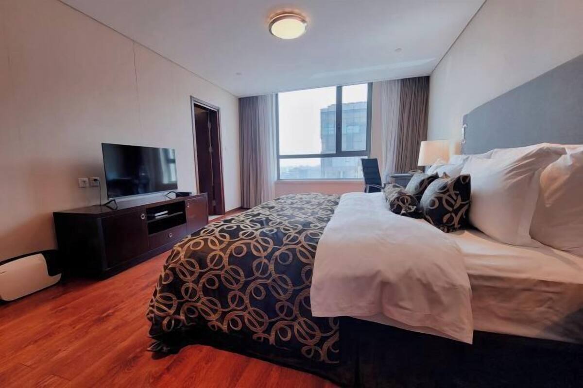 Ein Hotelzimmer mit Bett, Fernseher, Schreibtisch und Fenster.