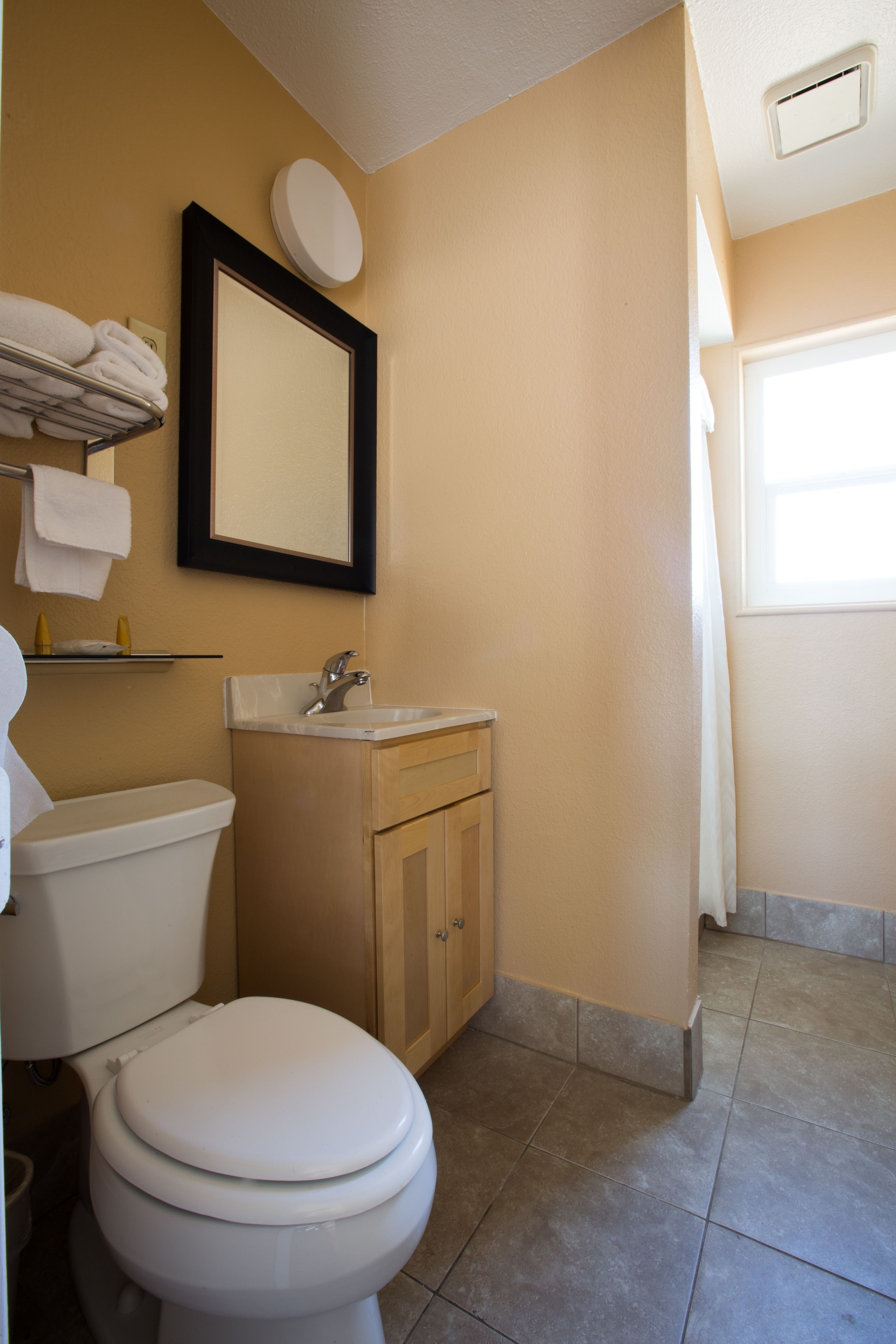 Une salle de bain équipée d’un WC, d’un lavabo, d’un miroir et d’un porte-serviettes.