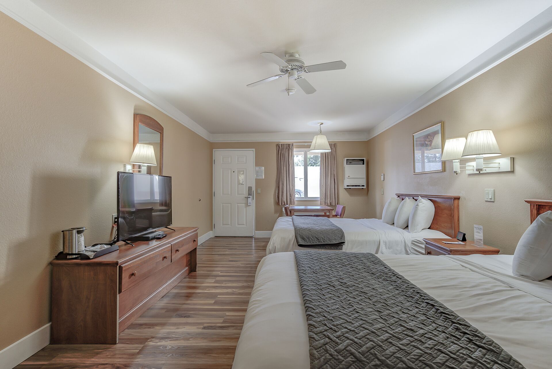 Habitación de hotel con cama, mesita de noche, televisor y ventilador de techo.