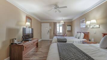 A hotel room with a bed, bedside table, TV, and a ceiling fan.