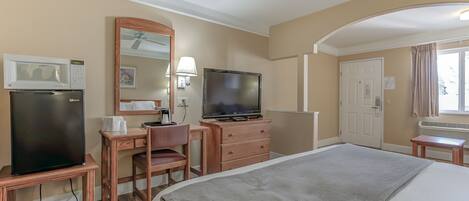 Une chambre d’hôtel équipée d’un lit, d’un bureau avec une chaise, d’une télévision, d’un four à micro-ondes et d’un réfrigérateur.