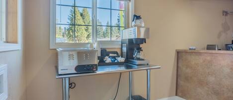 A kitchenette with a coffee machine, a toaster, and a sink.