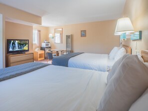 A hotel room with two beds, a television, a desk, and a chair.