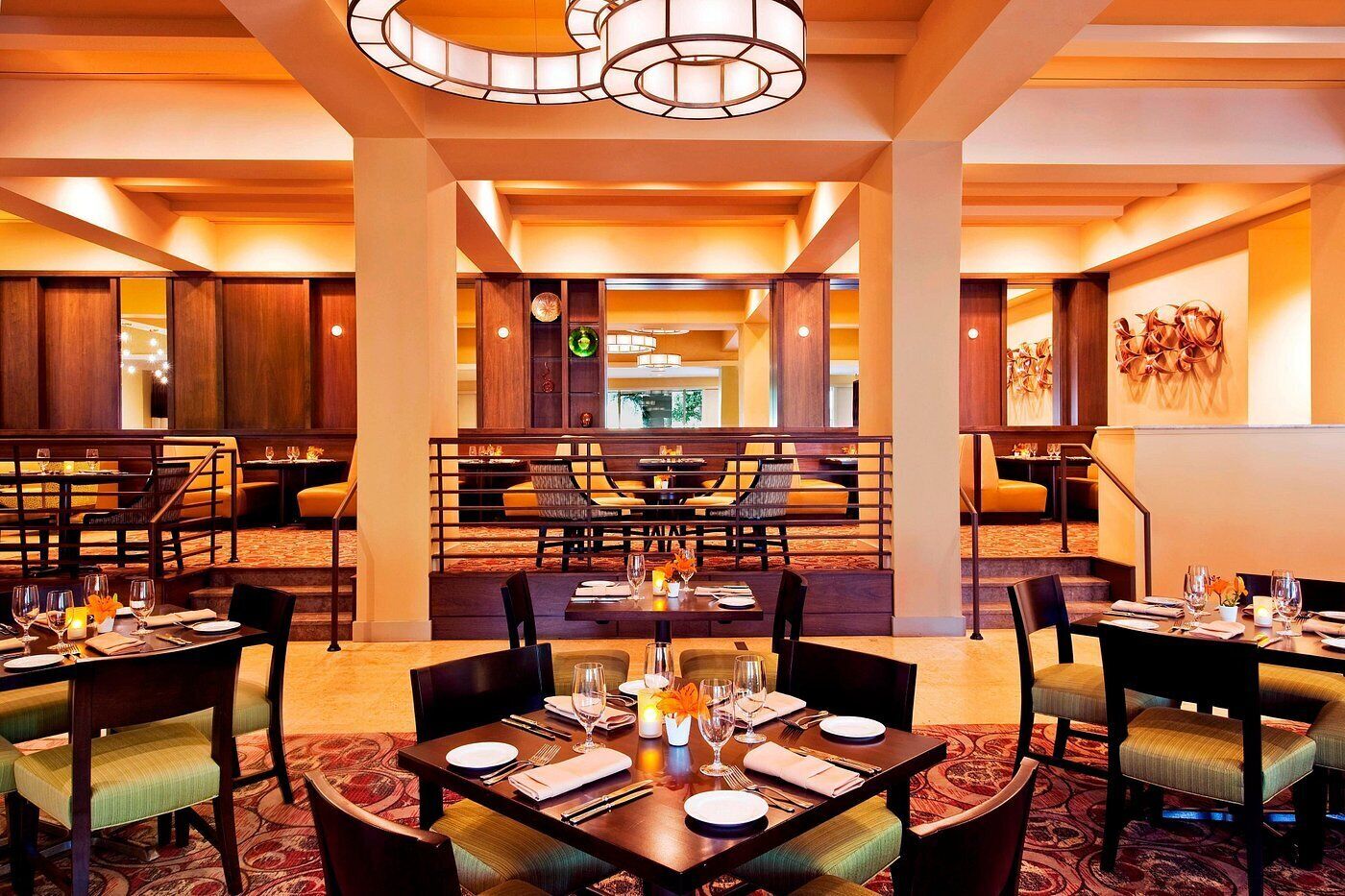 A restaurant with multiple dining tables and chairs, warm lighting, and a modern interior design.