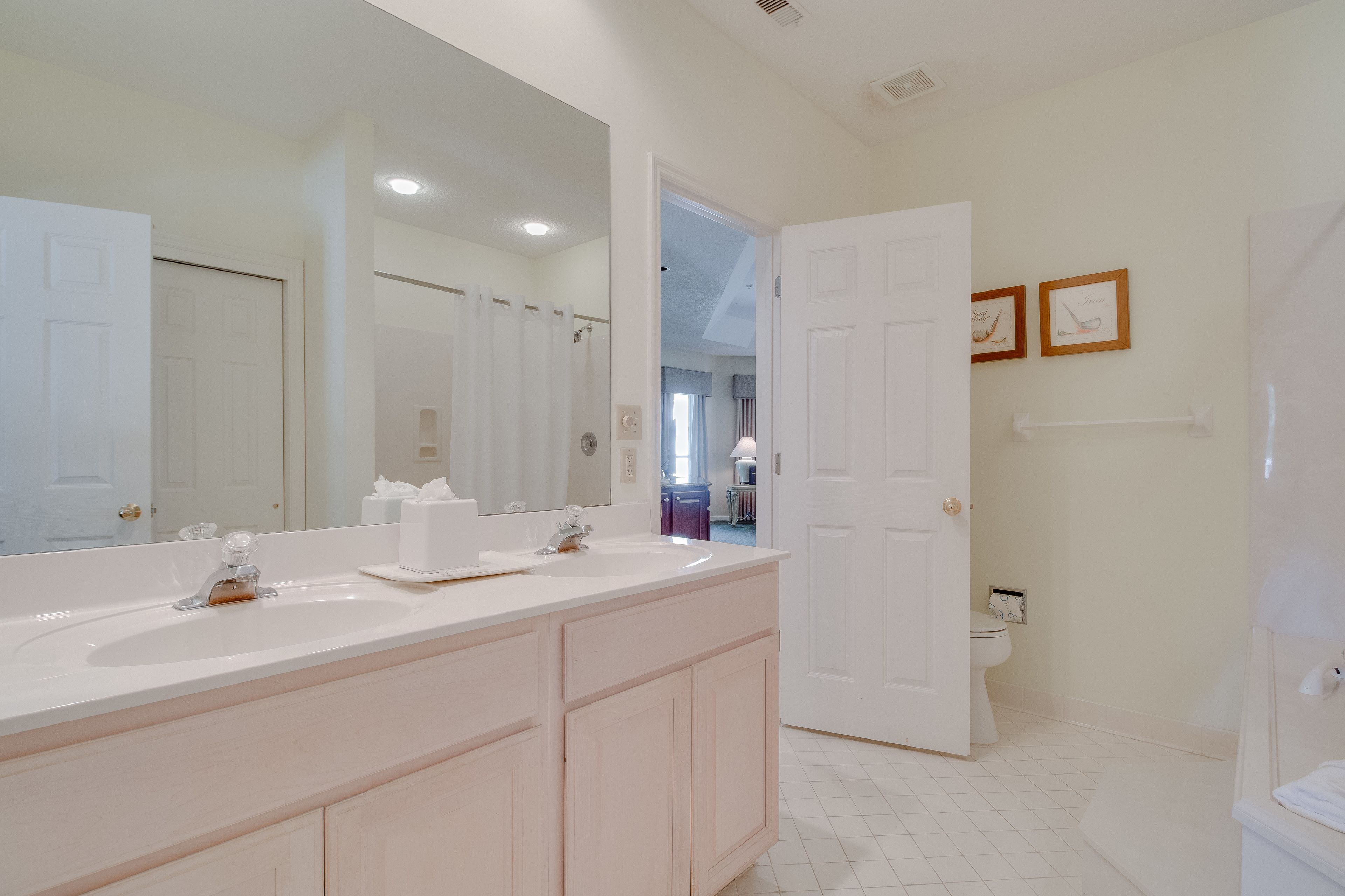 A bathroom with a double sink, a large mirror, and a toilet.
