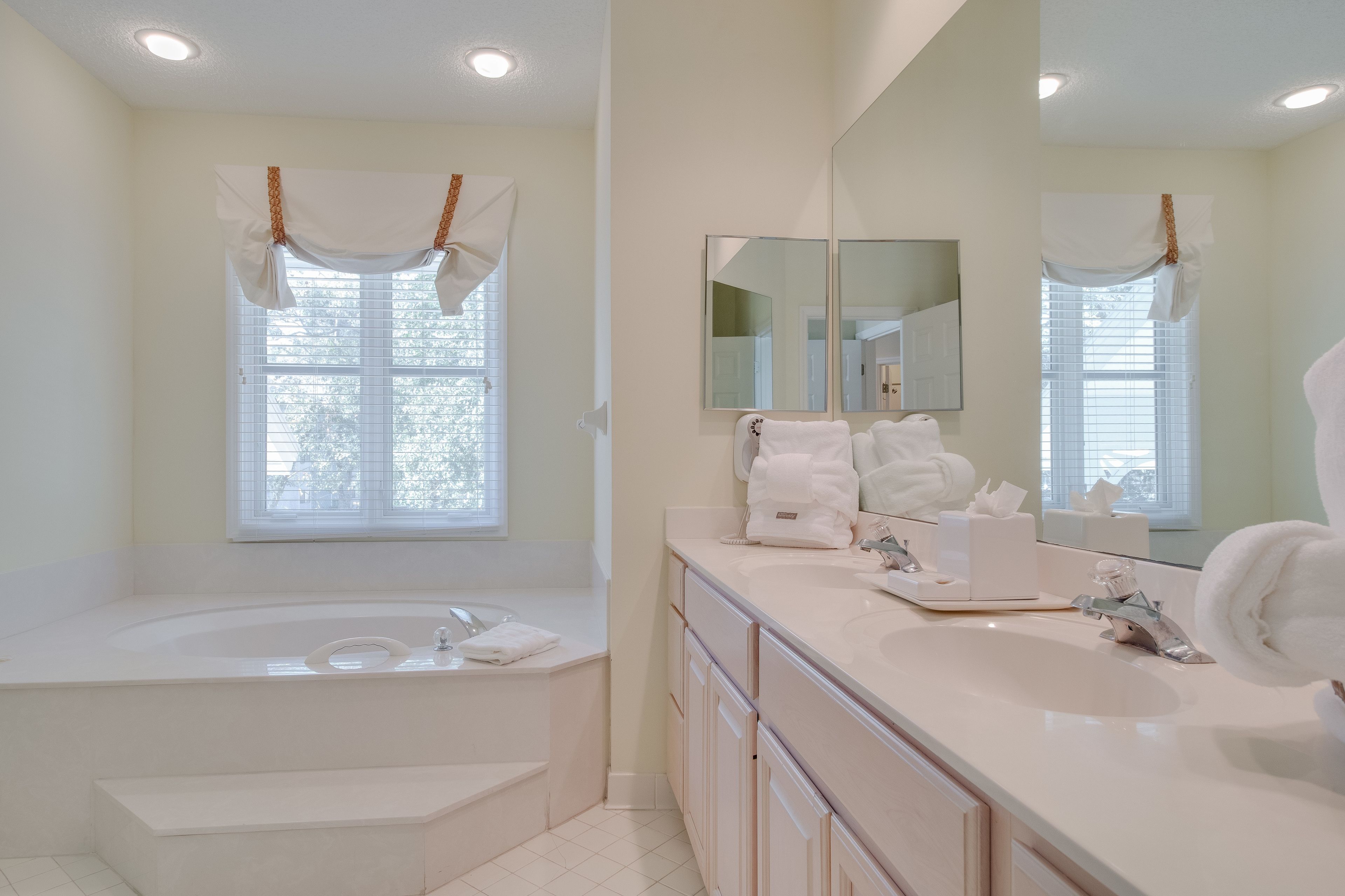 A modern bathroom with a freestanding bathtub, a large mirror, and a vanity with a sink.