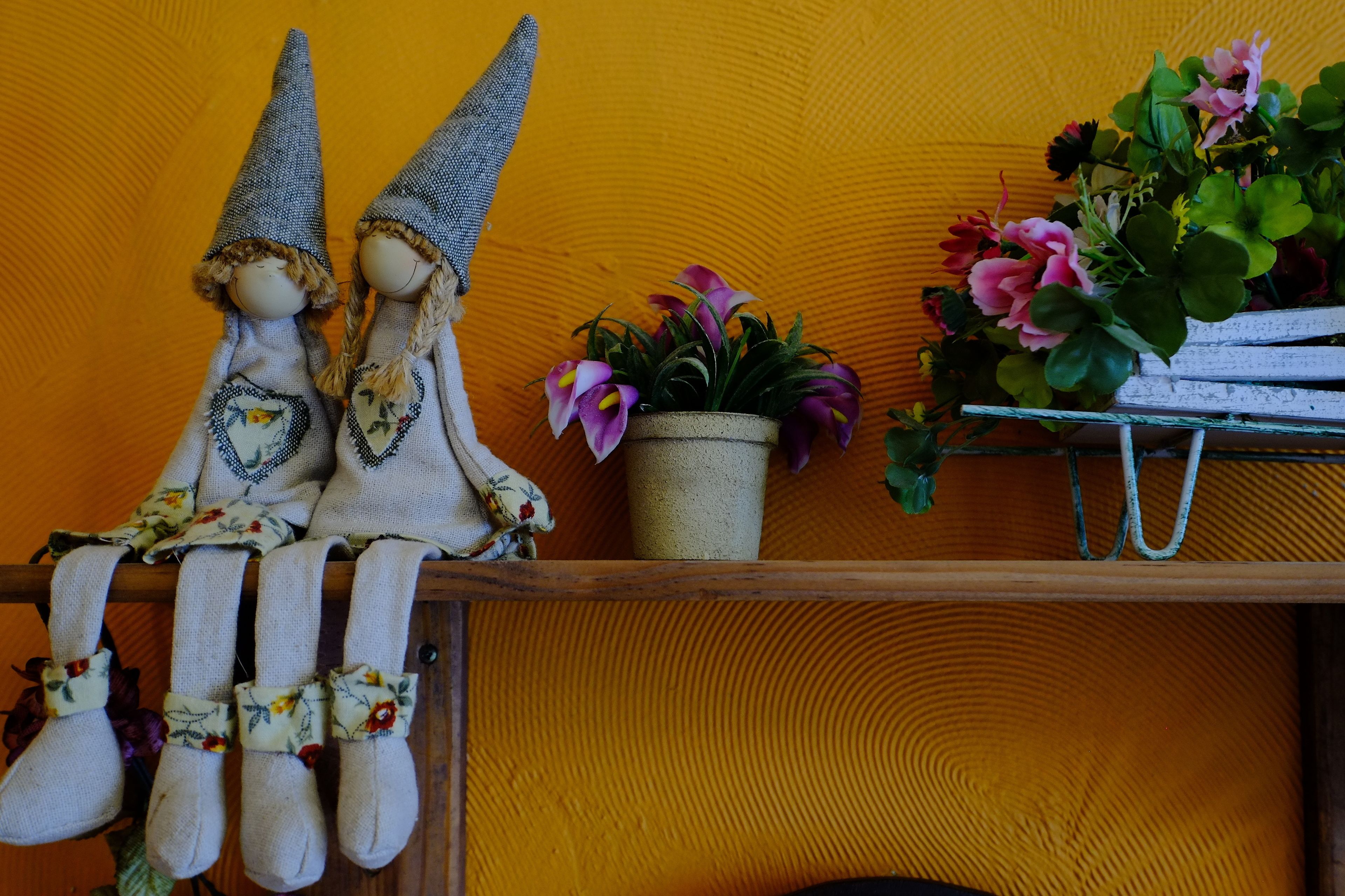 A shelf with two decorative figures, a potted plant, and a hanging plant.