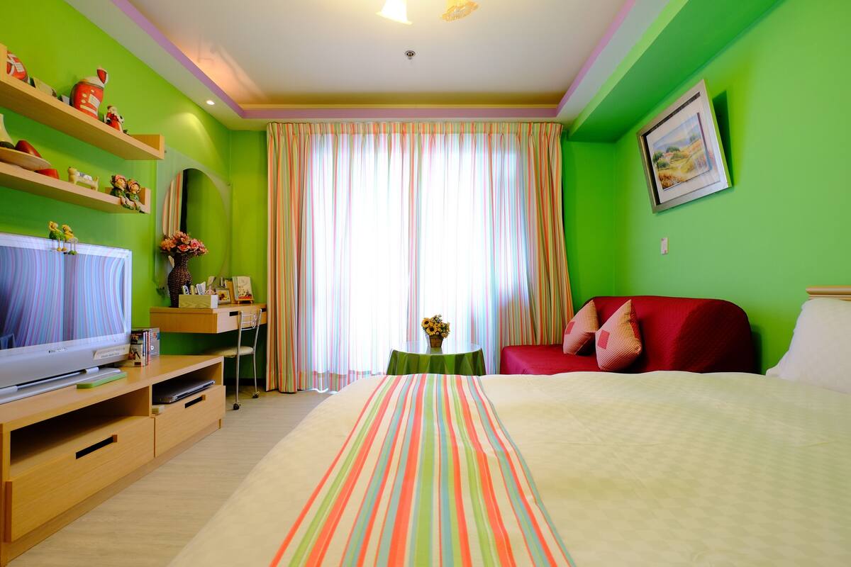 A hotel room with a bed, a TV, a desk, and a chair.