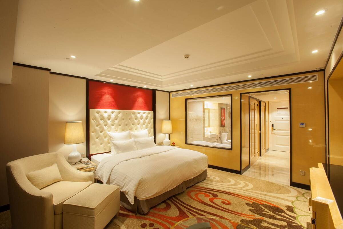 Una habitación de hotel con una cama grande, un sofá, un escritorio y un espejo.