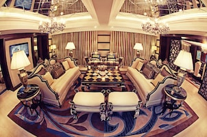 Uma sala de estar luxuosa com uma mesa de centro xadrez, sofás confortáveis e lustres elegantes.