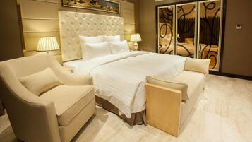 A spacious bedroom with a large bed, two bedside lamps, a sofa, and a decorative mirror.