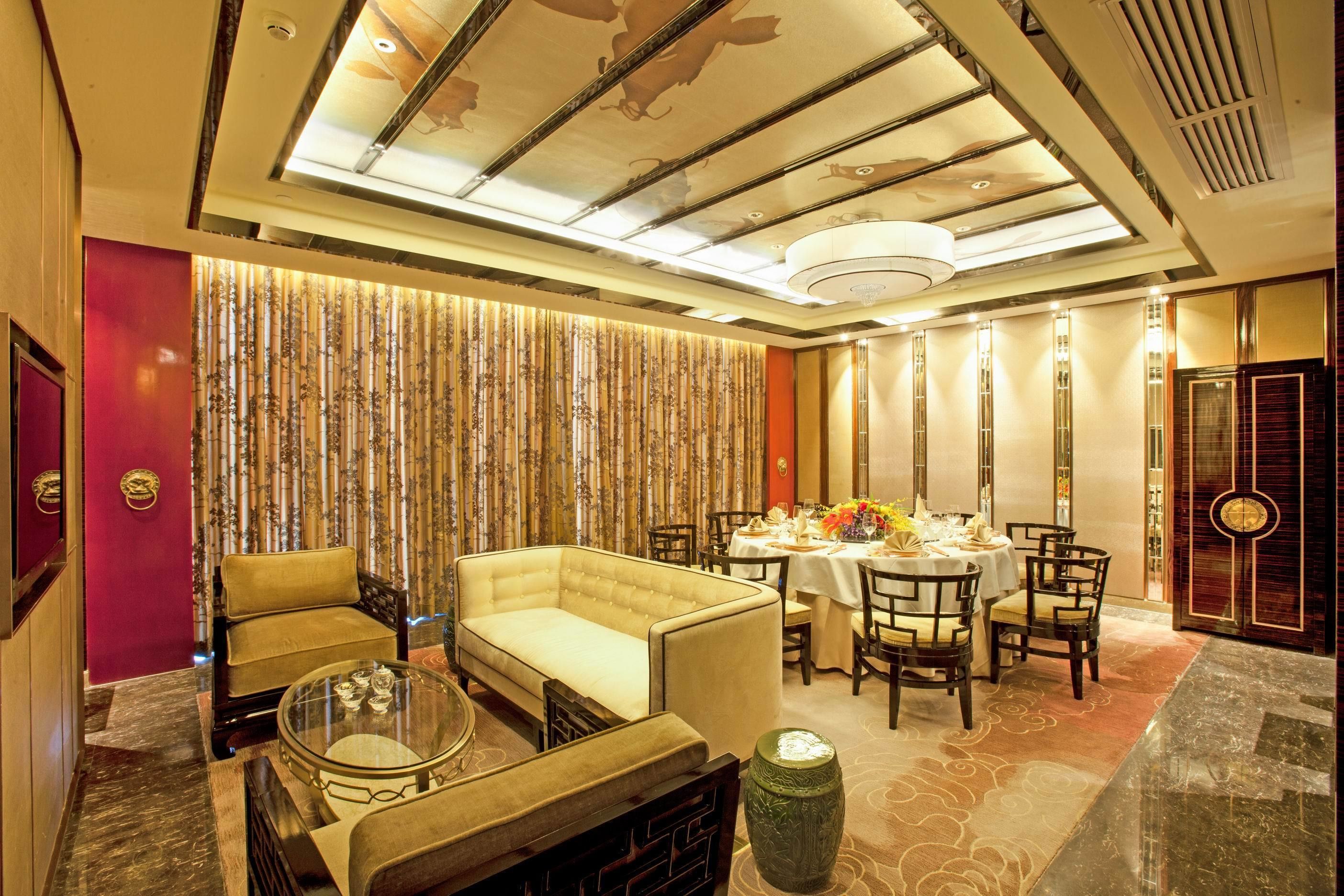 Un vestíbulo de hotel con un sofá, sillas, una mesa de comedor y una pared decorativa.