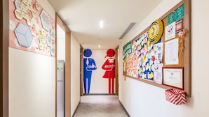 A hallway with a bulletin board on the right, featuring various notices and decorations. - CU Hotel Taipei (Taipei)