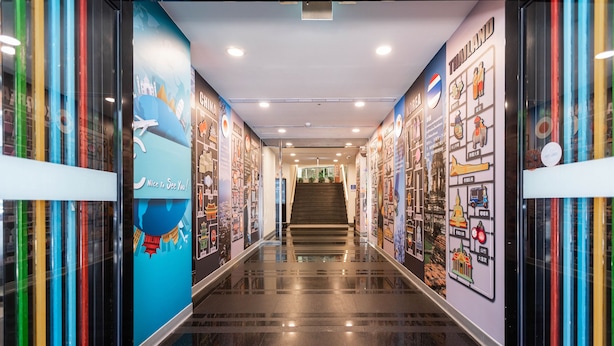 A modern hotel corridor with a polished floor, colorful vertical stripes, and walls adorned with cultural and travel-themed murals. - CU Hotel Taipei (Taipei)