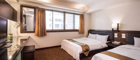 Ein Hotelzimmer mit zwei Betten, einem Schreibtisch mit Telefon und einem großen Fenster mit Vorhängen.
