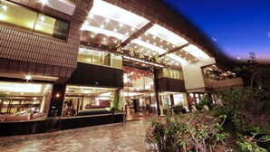 L’entrée d’un hôtel au design moderne, dotée de grandes fenêtres et d’une façade bien éclairée.