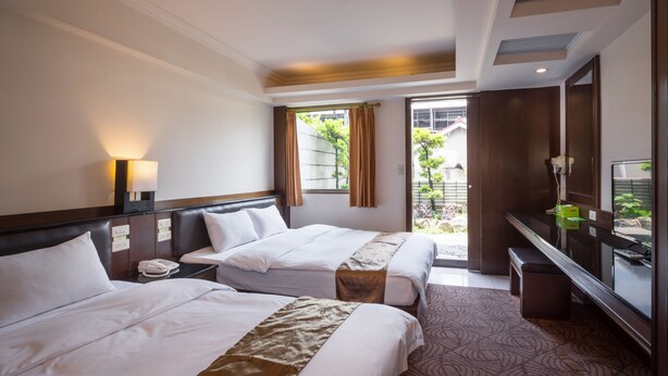 Une chambre d’hôtel avec deux lits, un bureau, une télévision et une fenêtre avec des rideaux.
