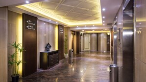 Un hall d’hôtel comprenant un comptoir d’accueil, des panneaux d’orientation, une plante en pot et un sol propre et ciré.