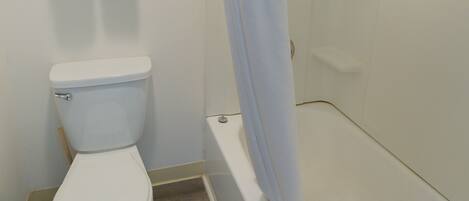 A bathroom with a toilet, a shower curtain, and a towel rack with two towels.