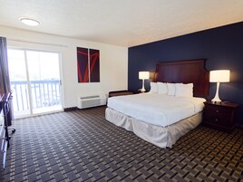 Habitación de hotel con una cama grande, dos mesitas de noche con lámparas, un ventanal con vistas y aire acondicionado instalado en la pared.