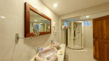 A bathroom with two marble sinks, a wooden door, and a glass shower enclosure.