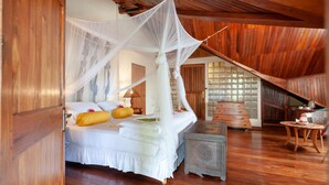 A bedroom with a four-poster bed, wooden flooring, and a traditional wooden ceiling. - Nosy Be Hotel & Spa (Nosy Be)