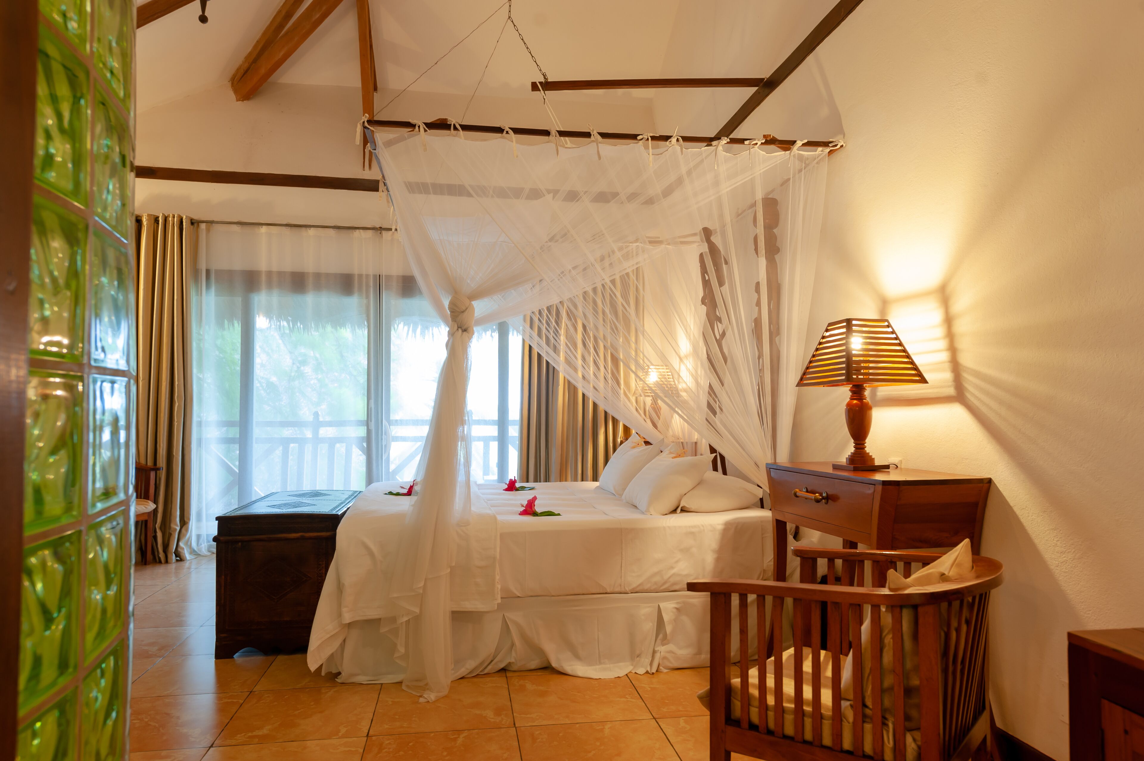 A bedroom with a canopy bed, a bedside table with a lamp, and a crib.