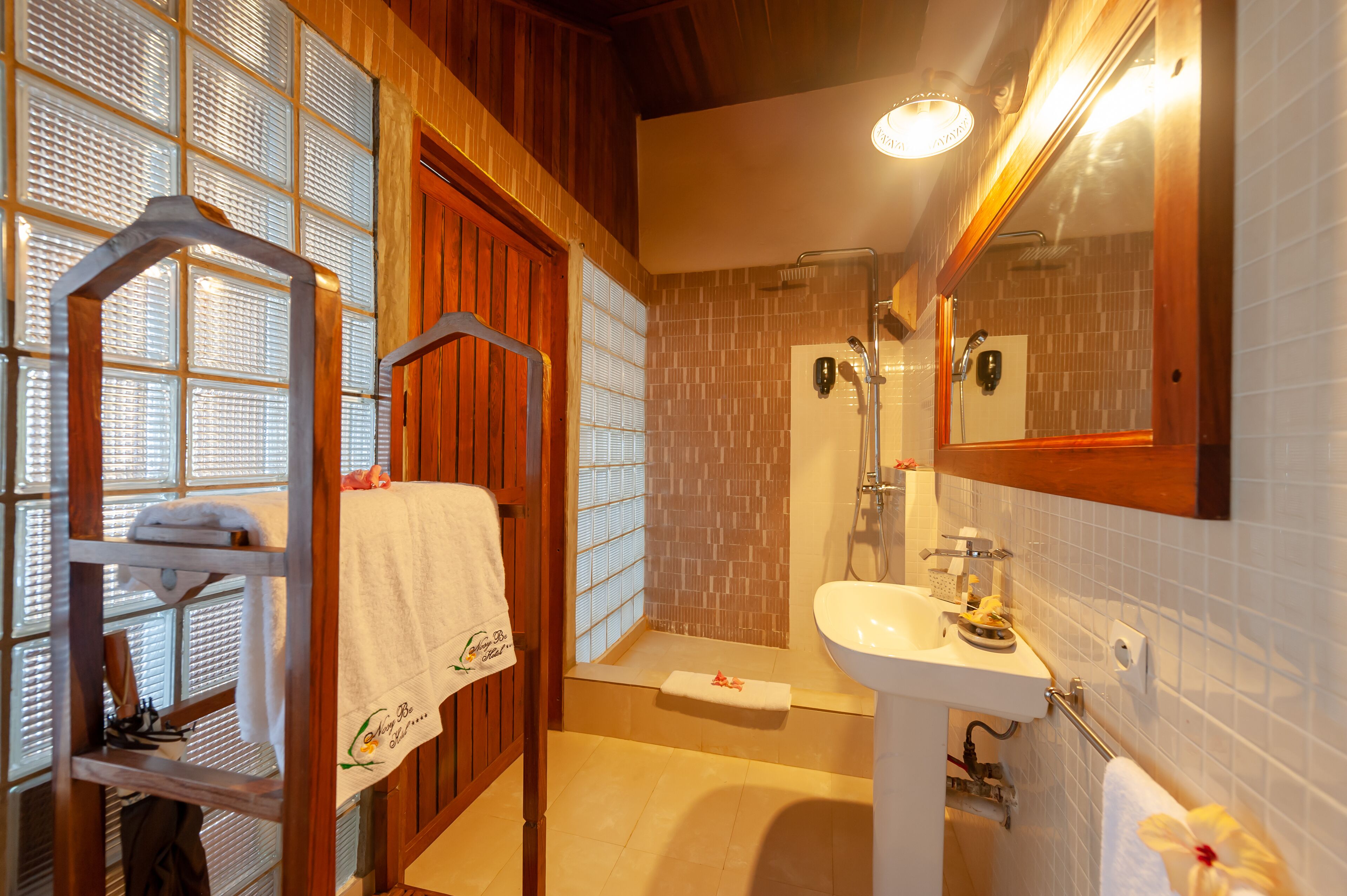 A bathroom with a wooden vanity, a sink, a mirror, and a shower.