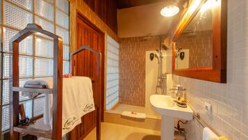 Une salle de bain avec un meuble-lavabo en bois, un évier, un miroir et une douche.