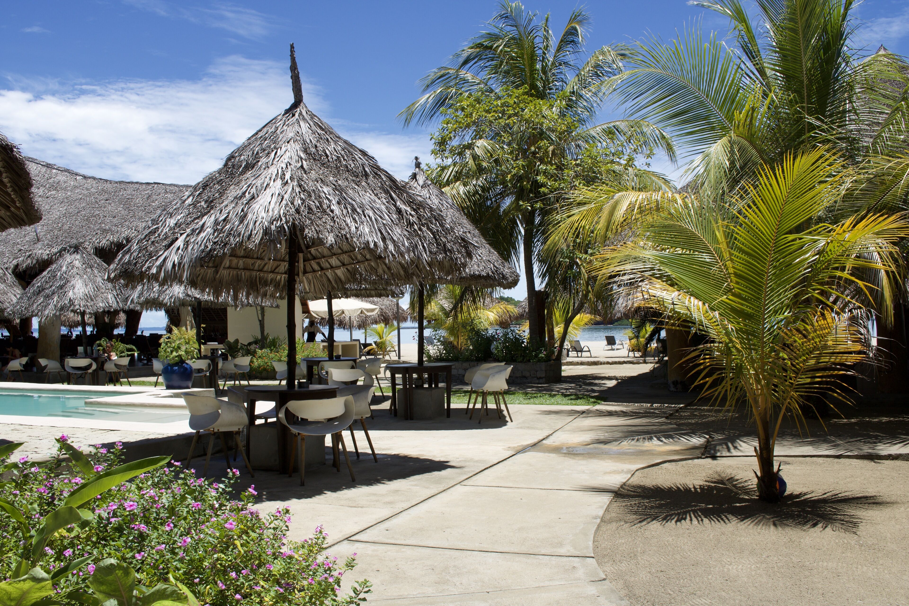 Un resort con estructuras de techo de paja, asientos al aire libre y una piscina.