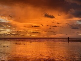 Ein Strand bei Sonnenuntergang, eine Person spaziert.