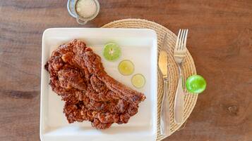 A plate of fried fish with lime wedges on a wooden table.