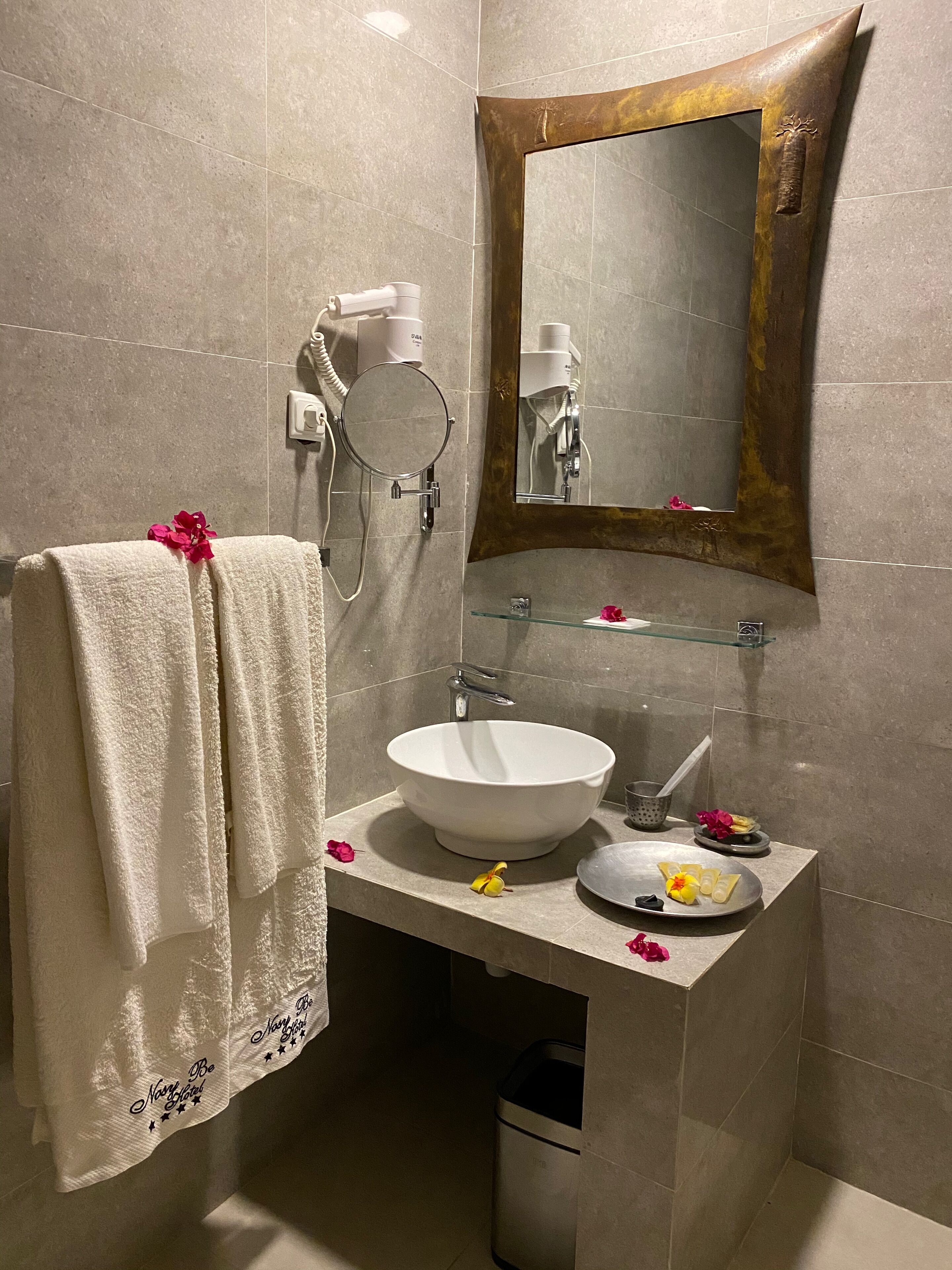 A bathroom with a white sink, a mirror, and a towel with a flower.
